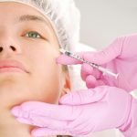 Close-up of a beautician administering facial injection treatment to a woman in a clinical setting.